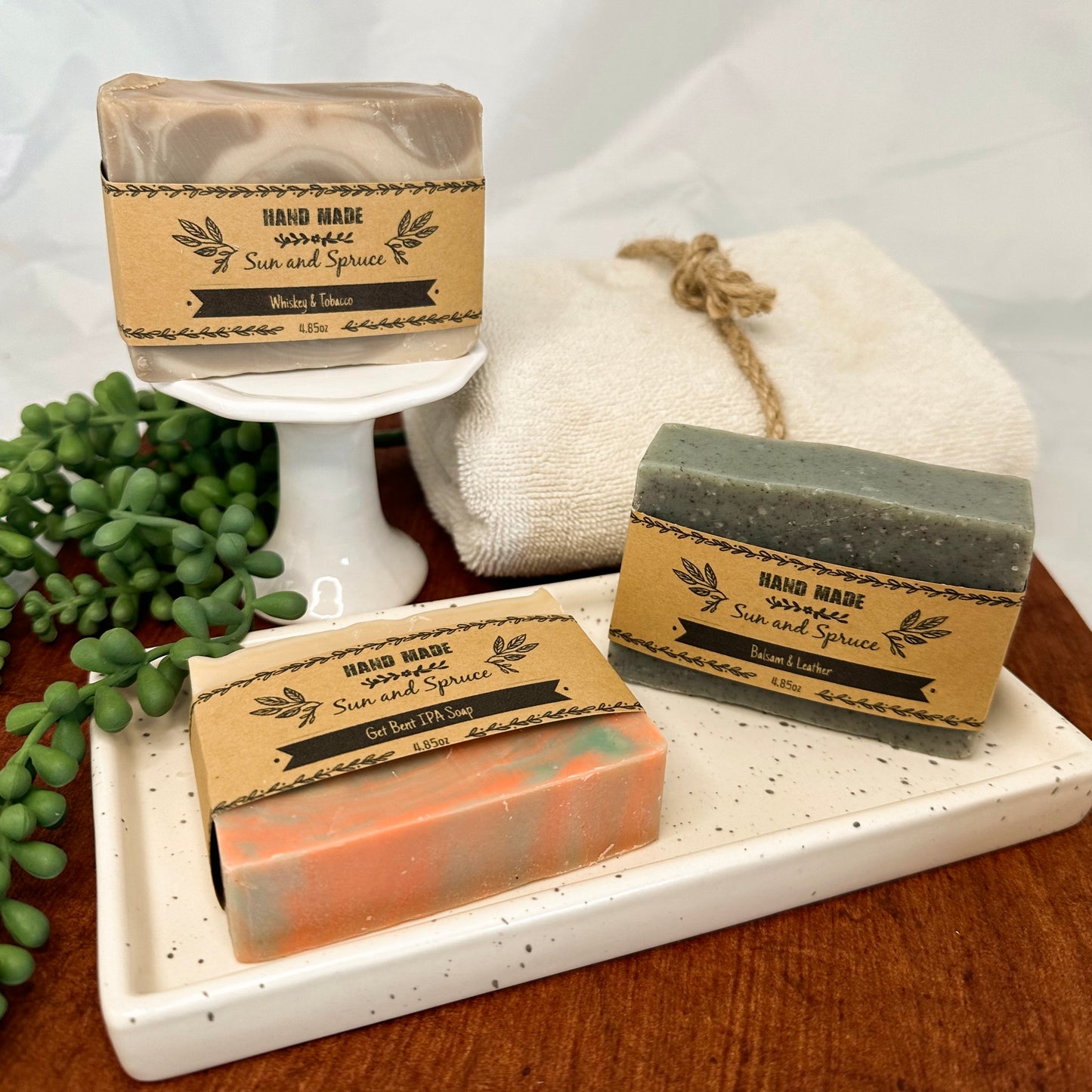 A variety of Sun and Spruce Handmade Soaps including scents such as Whiskey and Tobacco, Balsam and Leather, and Get Bent IPA Soap